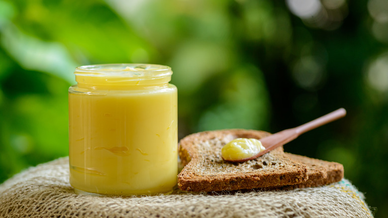 Ghee in glass jar and on wooden spoon