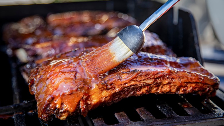 brushing sauce on grilling beef ribs