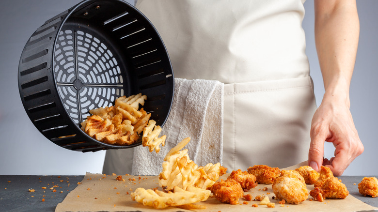 pouring french fries from air fryer basket