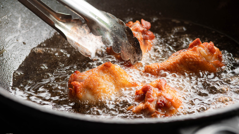 chicken frying in pan of oil