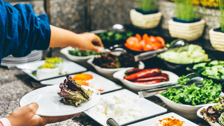 Woman's hand picking salad at buffet