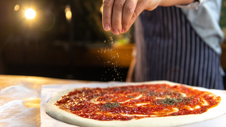 Sprinkling oregano over pizza