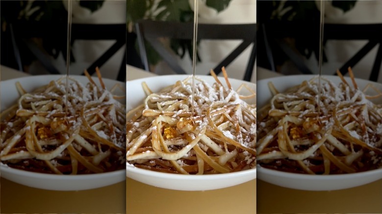 Pouring syrup on pancake spaghetti in a bowl