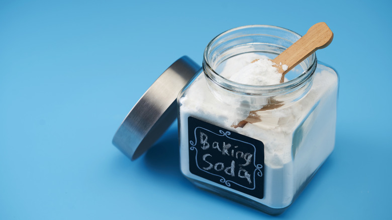 A jar of baking soda with a spoon in it.