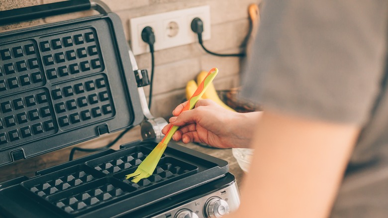 Person oiling a waffle maker