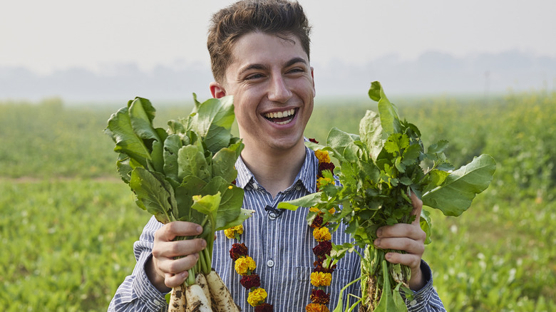 Eitan Bernath holds green veggies in field