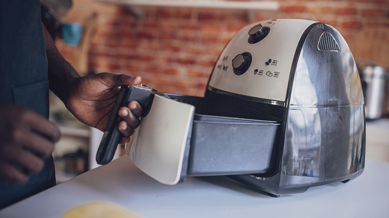 Hand pulling out air fryer drawer 