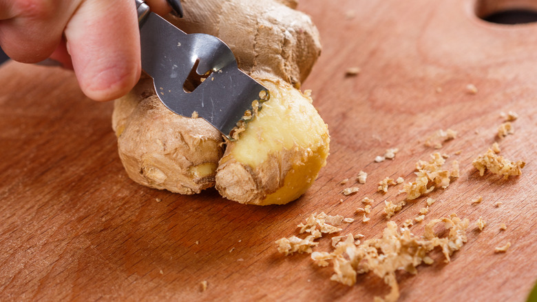 Peeling ginger on wooden board