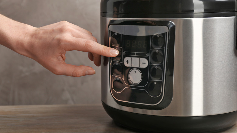 Person pressing button on multicooker 