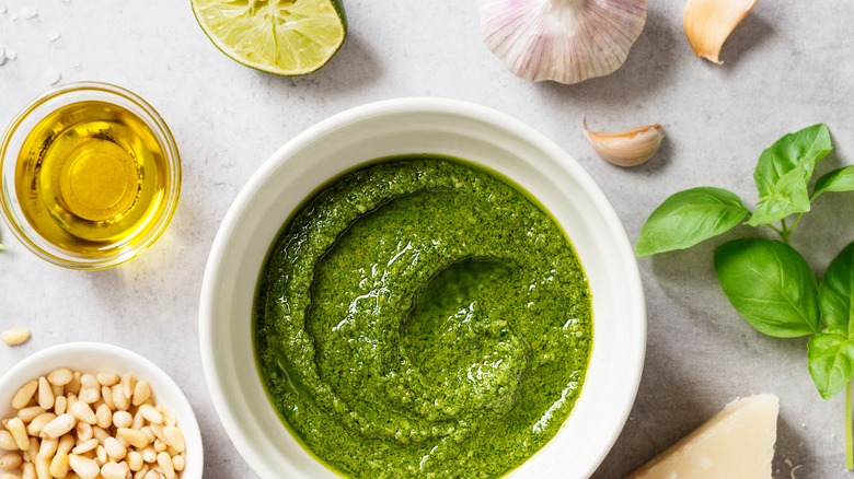 a bowl of pesto surrounded by fresh ingredients