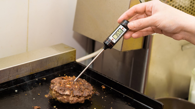 thermometer reading the temperature of burger