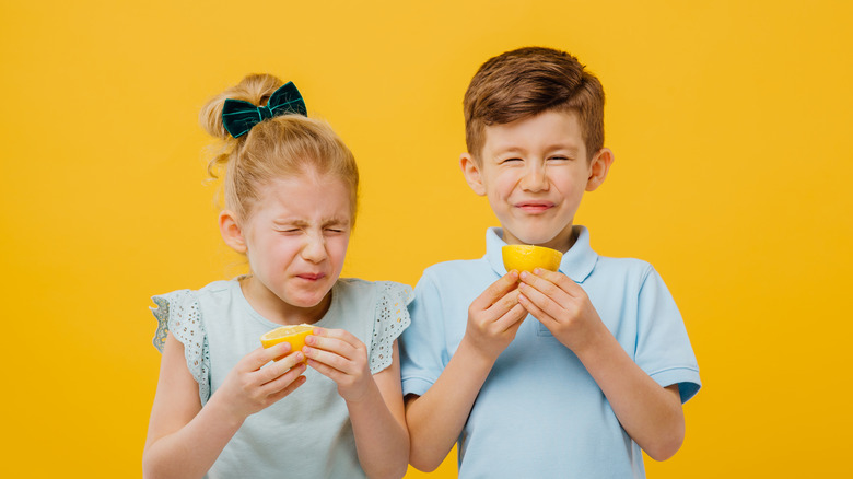 Two kids tasting lemons