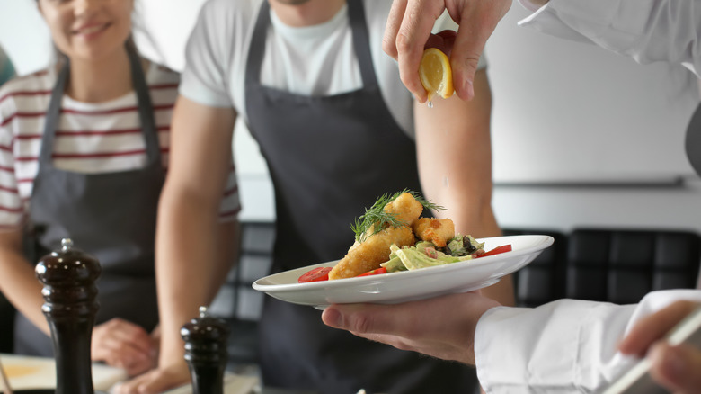 A chef squeezes lemon on a dish