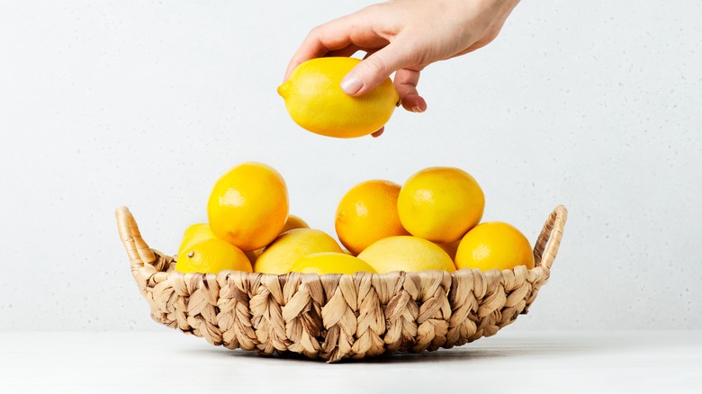 Someone grabbing a lemon from a basket