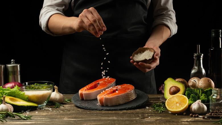 Chef seasoning salmon with salt