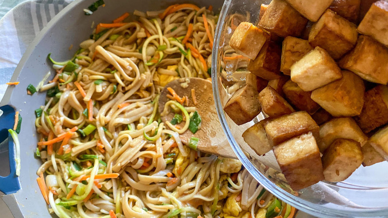 adding tofu cubes to noodles