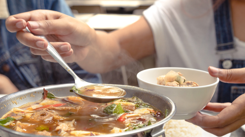 Woman serving tom yam soup 