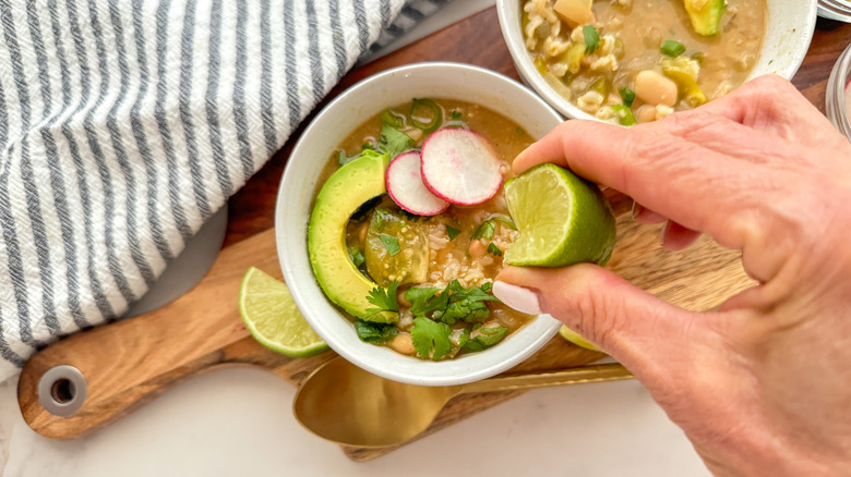 hand squeezing lime in chili