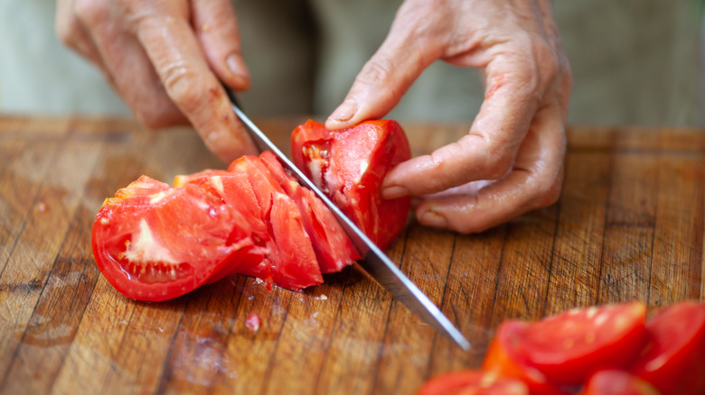 hands cutting a tomato