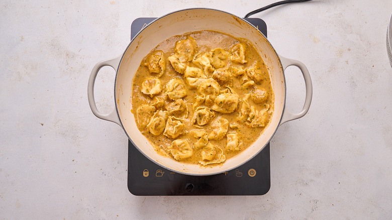 tossing tortellini with pesto