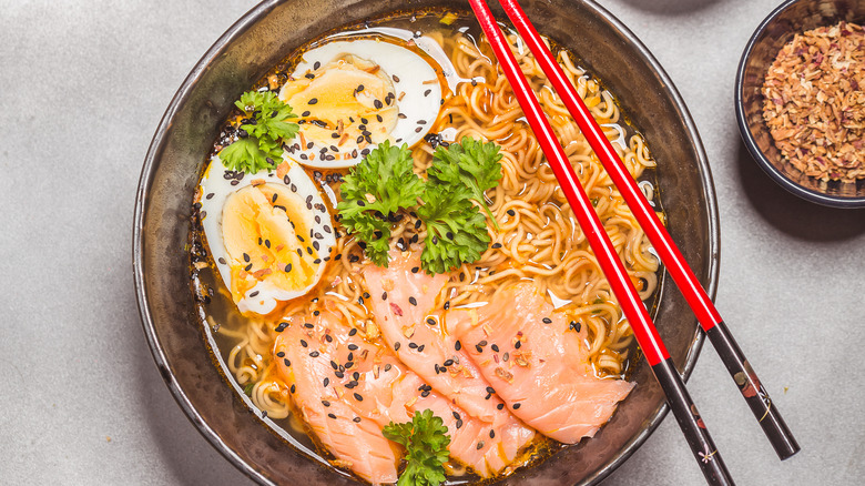 A bowl of instant ramen with eggs, cilantro, and salmon