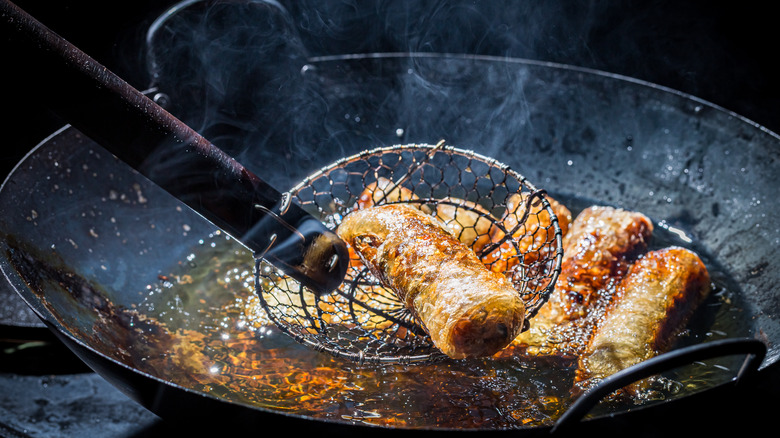 Spring rolls frying in a wok. 