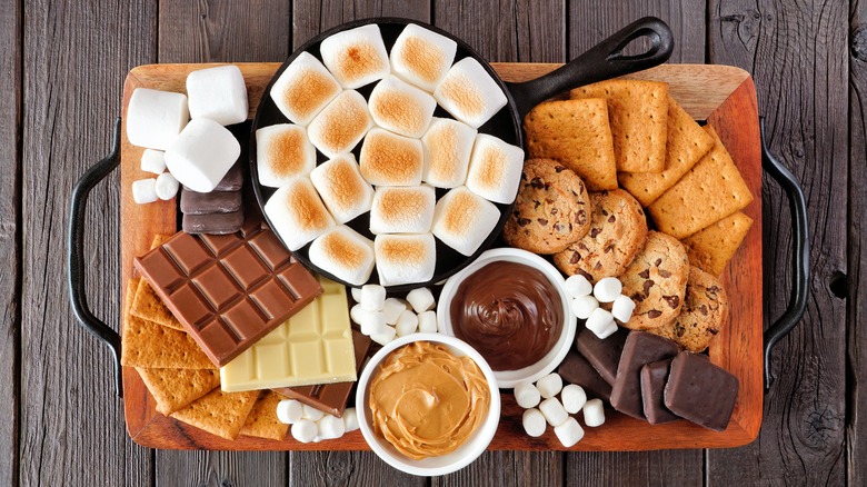 A plate of marshmallows, crackers, chocolate, and cookies
