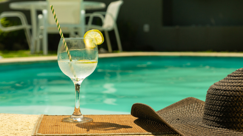 Glass of hard seltzer by pool, hat