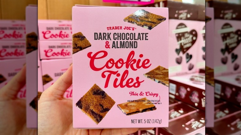 A hand holding a box of Trader Joe's Dark Chocolate and Almond Cookie Tiles