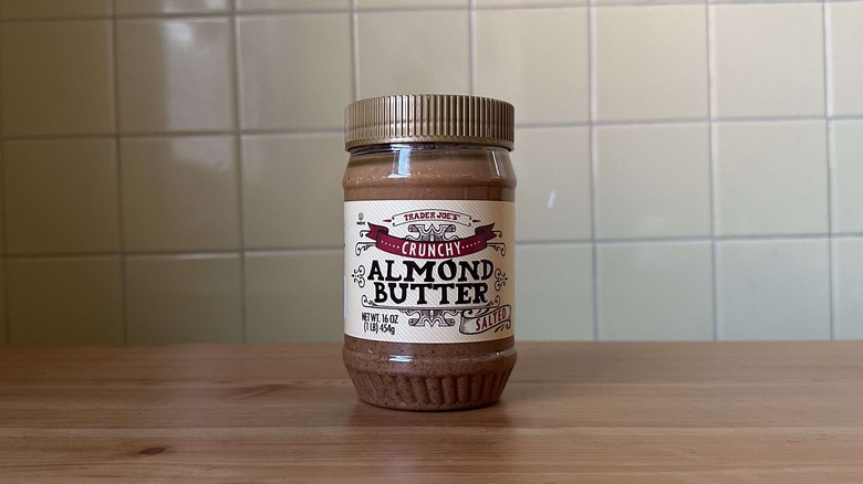 Crunchy Almond Butter Salted on wooden table with yellow tile background