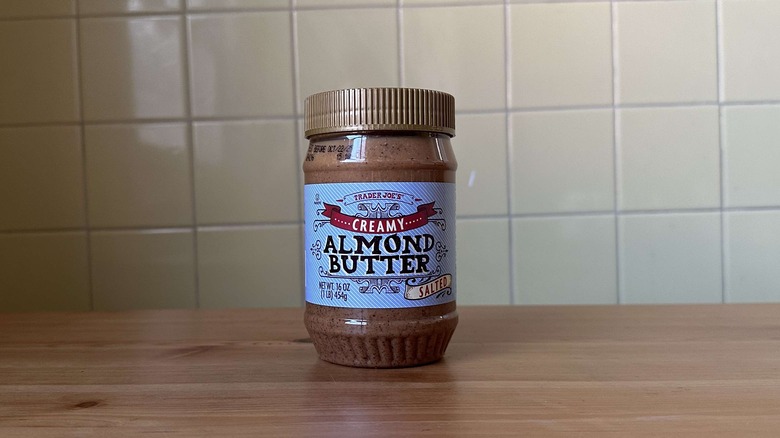 Creamy Almond Butter Salted on wooden table with yellow tile background