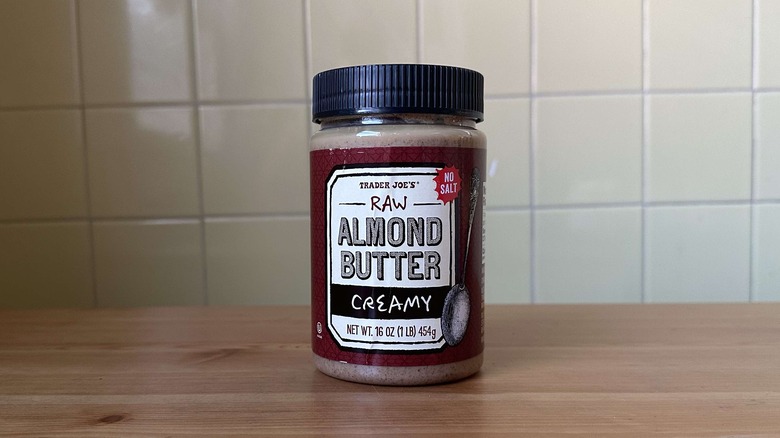 Raw Almond Butter Creamy on wooden table with yellow tile background