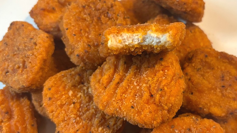 Close up of pile of Trader Joe's Spicy Chicken Nuggets, one with bite taken from it