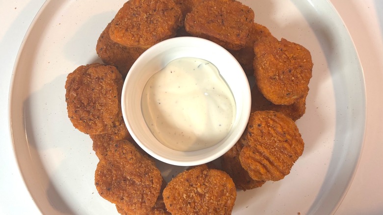 Trader Joe's Spicy Chicken Nuggets around a small bowl of ranch dressing on white plate.