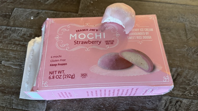 Box of opened Trader Joe's strawberry mochi ice cream with one bitten on top