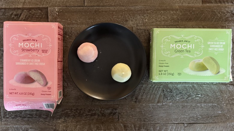 Two boxes of Trader Joe's mochi ice cream on wooden surface with black plate holding the desserts