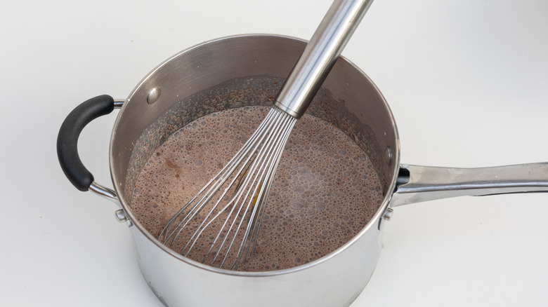 whisking custard ingredients in saucepan