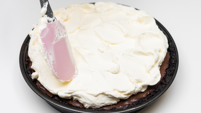 spreading cream topping on pie