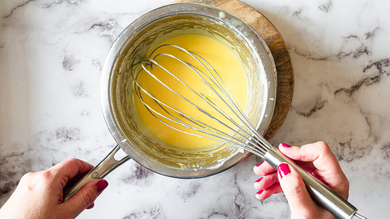 metal bowl with hollandaise atop a saucepan