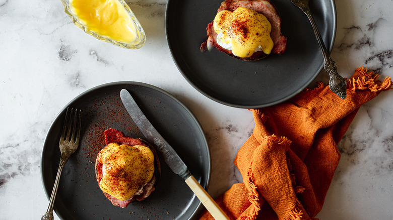 two eggs benedict on black plates