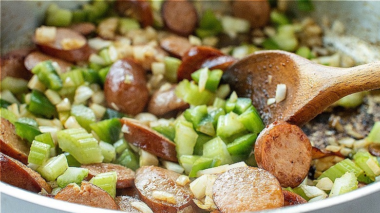 wooden spoon stirring celery, onion, and pepper