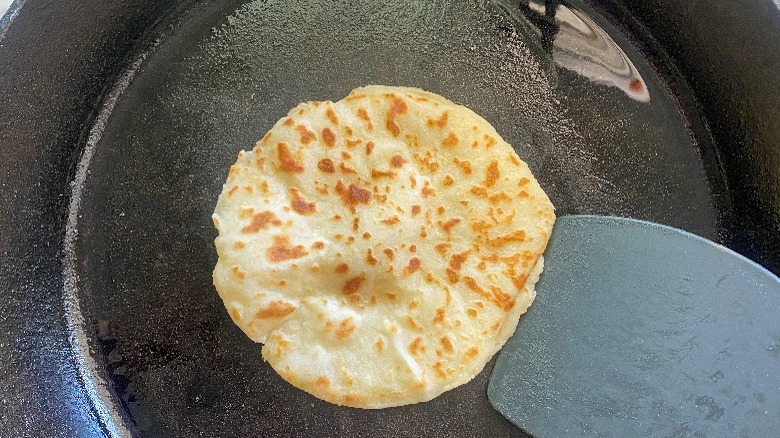 flatbread in skillet with spatula 