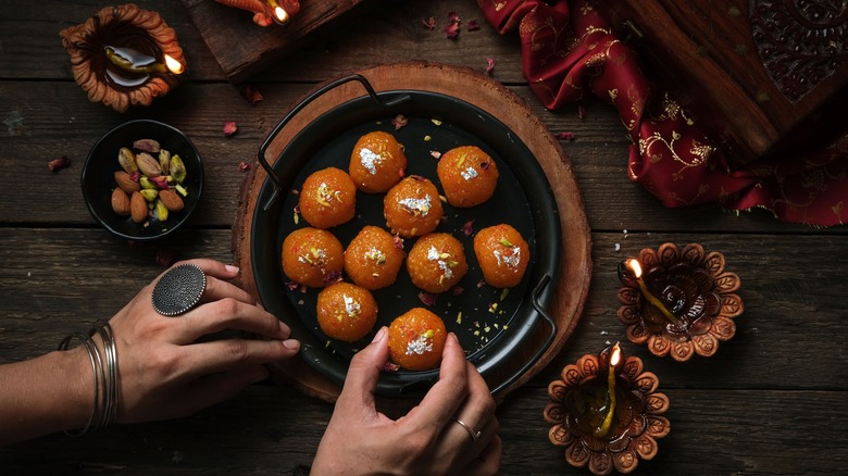 Hand grabbing gulab jamun