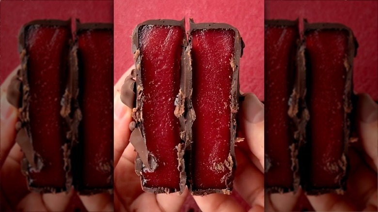 two split halves of a chocolate covered cranberry sauce disc