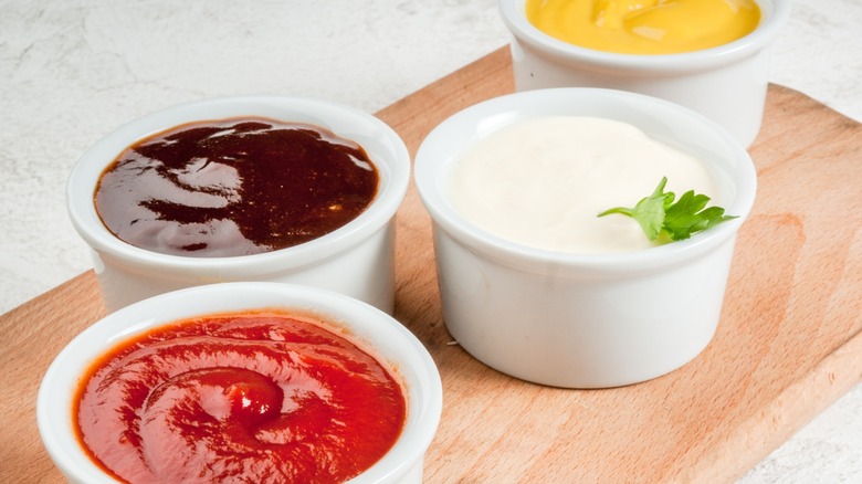 A set of dipping sauces on a wooden board