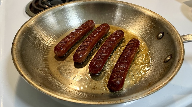 hot dogs cooking in skillet