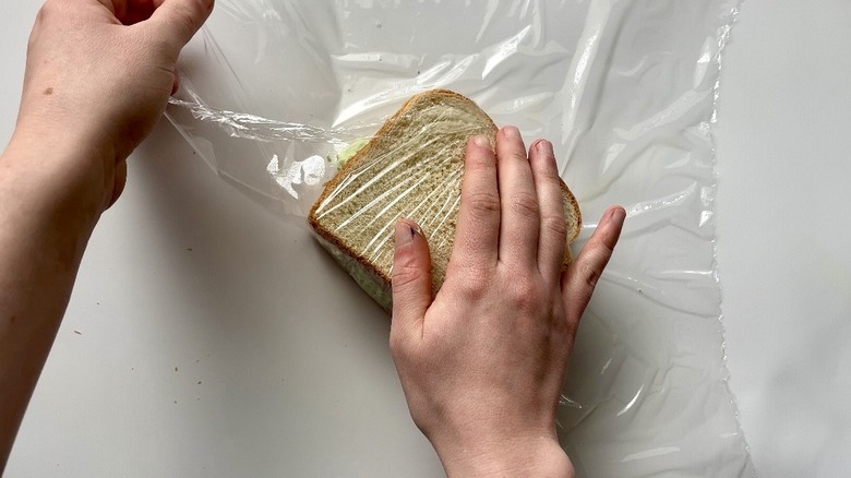 hands wrapping sandwich in plastic