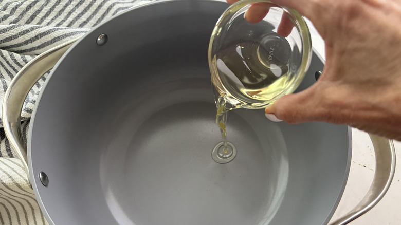 Hand pouring oil into a pot