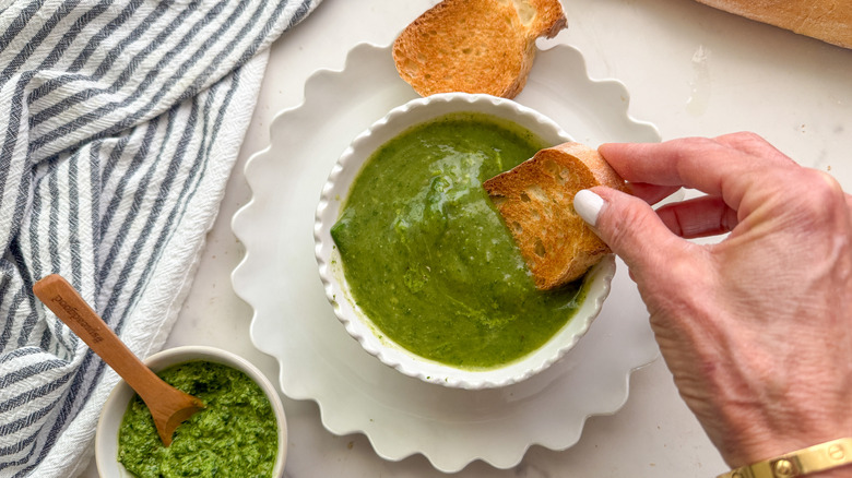 hand dipping bread in soup