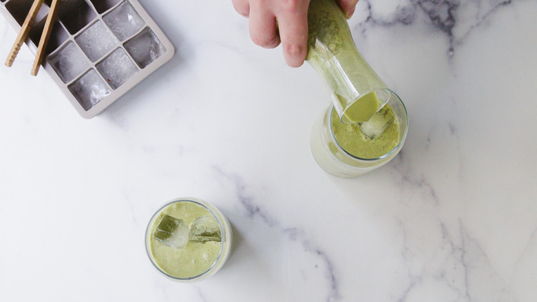 Pouring matcha mocktail into glasses with ice